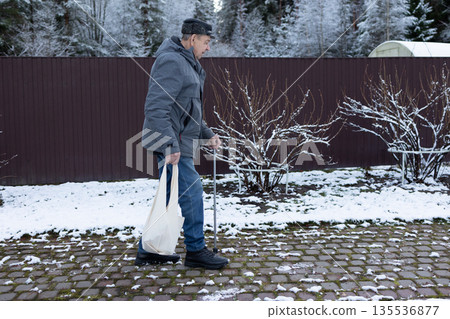Elderly Man Walking With Cane In Snowy Courtyard 135536877
