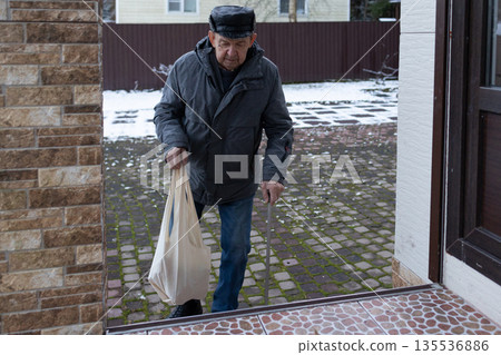 Elderly Man Walking With Cane In Snowy Courtyard Elderly Man Walking With Cane In Snowy Courtyard 135536886