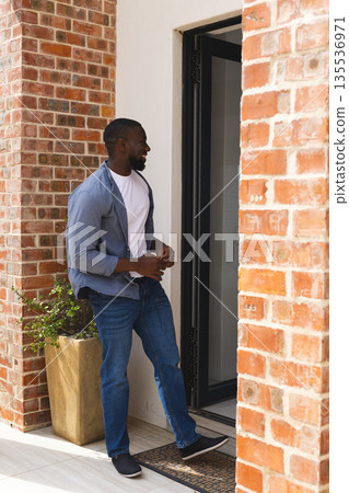 Man entering modern home, smiling and enjoying relaxed afternoon moment Man entering modern home, smiling and enjoying relaxed afternoon moment 135536971