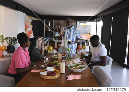 Family enjoying festive meal together, sharing stories and laughter at dining table 135536979