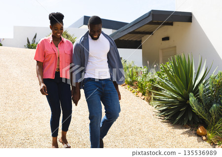 Couple walking outdoors on sunny day, enjoying time together and smiling 135536989