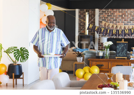 Man carrying tray with food at retirement party, surrounded by festive decorations Man carrying tray with food at retirement party, surrounded by festive decorations 135536990
