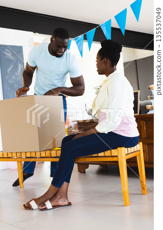 Couple unpacking cardboard box at home, smiling and enjoying new beginnings 135537049