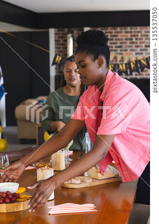 Woman arranging food on table at retirement party, preparing for celebration 135537050