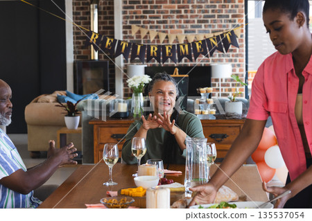 Family celebrating retirement with food and drinks at home, sharing joyful moments Family celebrating retirement with food and drinks at home, sharing joyful moments 135537054