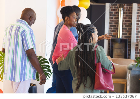 Group of friends joyfully entering party, carrying gifts and chatting happily Group of friends joyfully entering party, carrying gifts and chatting happily 135537067