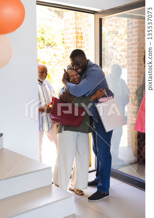 Family celebrating joyful reunion at home, exchanging warm hugs and gifts Family celebrating joyful reunion at home, exchanging warm hugs and gifts 135537073