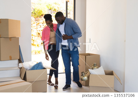 Couple unpacking boxes in new home, smiling and enjoying fresh start together Couple unpacking boxes in new home, smiling and enjoying fresh start together 135537106
