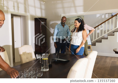 Family gathering around dining table, smiling and preparing for celebration at home 135537160