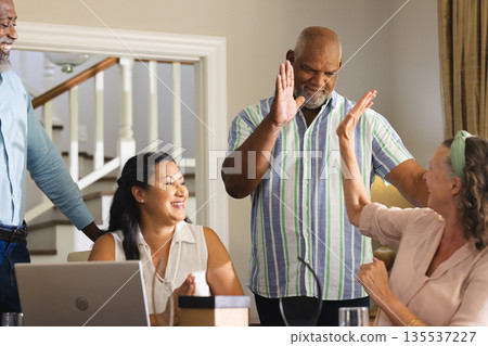 Seniors celebrating success at home, giving high fives and smiling together 135537227