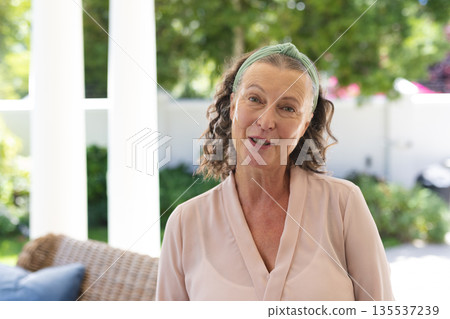 Smiling senior woman enjoying outdoor gathering, looking content and relaxed 135537239