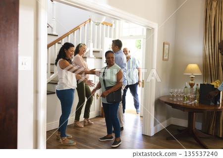 Family welcoming guests at home, smiling and preparing for celebration Family welcoming guests at home, smiling and preparing for celebration 135537240