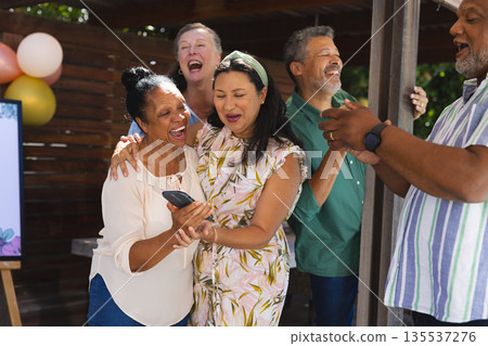 Seniors celebrating together outdoors, laughing and sharing moments with smartphone Seniors celebrating together outdoors, laughing and sharing moments with smartphone 135537276