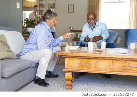 Playing board game, African American men on couch having friendly conversation Playing board game, African American men on couch having friendly conversation 135537277