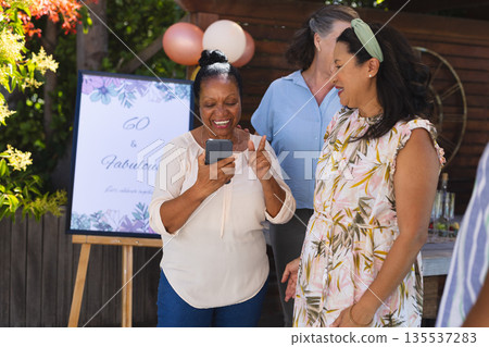 Celebrating 60th birthday, African American woman joyfully sharing moment with friends Celebrating 60th birthday, African American woman joyfully sharing moment with friends 135537283