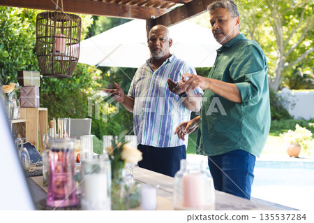 Seniors enjoying outdoor celebration, arranging decorations by poolside in garden 135537284
