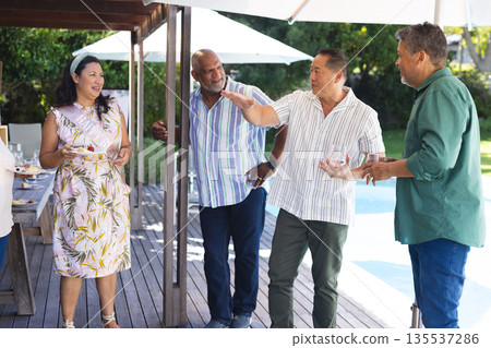 Group of seniors enjoying outdoor gathering, laughing and sharing stories by pool Group of seniors enjoying outdoor gathering, laughing and sharing stories by pool 135537286