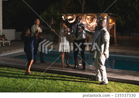 Celebrating by poolside, seniors raising glasses and having evening together 135537330