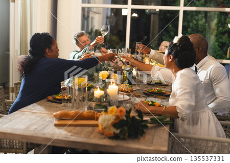 Family celebrating with dinner, raising glasses in joyful toast at home 135537331