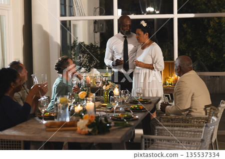 African American couple celebrating anniversary with friends at elegant dinner party 135537334