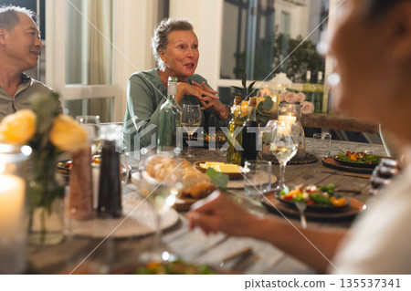 Seniors enjoying dinner party, sharing stories and laughter around festive table 135537341