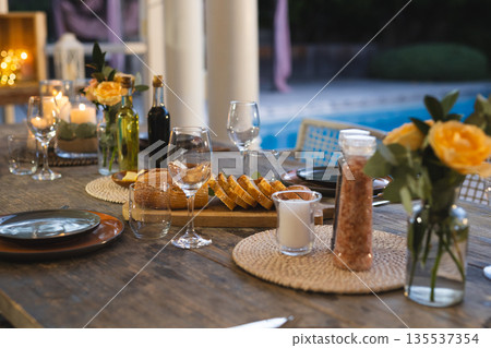 Elegant outdoor dining setup with wine glasses and bread by poolside Elegant outdoor dining setup with wine glasses and bread by poolside 135537354