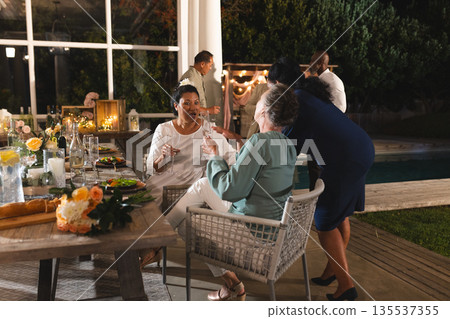 Seniors enjoying outdoor celebration, laughing and toasting with friends by pool Seniors enjoying outdoor celebration, laughing and toasting with friends by pool 135537355