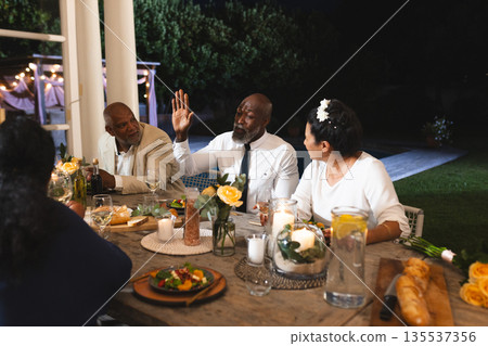 African American man sharing story at outdoor dinner party with friends African American man sharing story at outdoor dinner party with friends 135537356