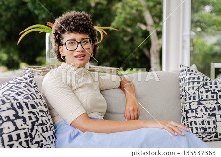 Smiling woman relaxing on sofa at home, enjoying peaceful afternoon indoors 135537363