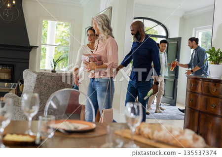 Guests arriving at elegant home, smiling and chatting, ready for celebration Guests arriving at elegant home, smiling and chatting, ready for celebration 135537374