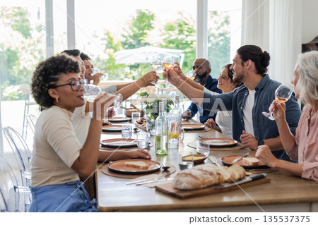 Friends and family toasting with wine glasses at elegant dining table celebration 135537375