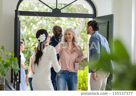 Guests arriving at wedding, greeting bride with smiles and gift at entrance Guests arriving at wedding, greeting bride with smiles and gift at entrance 135537377