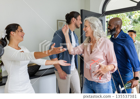 Guests arriving with gifts, warmly greeting bride at home during wedding celebration Guests arriving with gifts, warmly greeting bride at home during wedding celebration 135537381