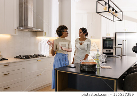 African American woman and friend discussing wedding plans in modern kitchen 135537399