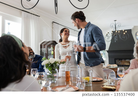 Couple joyfully toasting with friends at elegant wedding reception indoors 135537400