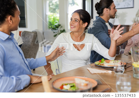 Guests enjoying lively conversation and delicious meal at wedding reception table 135537433