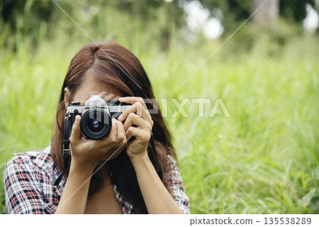 Close up hands Asian Women look at dslr digital camera vintage film style take a photo. Professional female photographer look at picture outdoor. Young woman hands shooting photo in green nature park 135538289