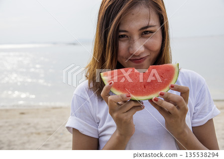 Women eat red watermelon organic hand holding red fruit high vitamins outdoor on tropical beach summertime. Young asian women smile enjoy eating tropical fruit happy time smile face. Female vegan Women eat red watermelon organic hand holding red fruit high vitamins outdoor on tropical beach summertime. Young asian women smile enjoy eating tropical fruit happy time smile face. Female vegan 135538294
