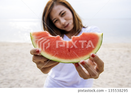 Women eat red watermelon organic hand holding red fruit high vitamins outdoor on tropical beach summertime. Young asian women smile enjoy eating tropical fruit happy time smile face. Female vegan Women eat red watermelon organic hand holding red fruit high vitamins outdoor on tropical beach summertime. Young asian women smile enjoy eating tropical fruit happy time smile face. Female vegan 135538295