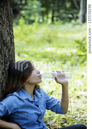 Vertical Young Woman Drinking Water bottle outdoor park traveler. Asian female drinking water bottle healthy happy person. Vertical images Beautiful asian women holding mineral drink bottle lifestyle 135538296