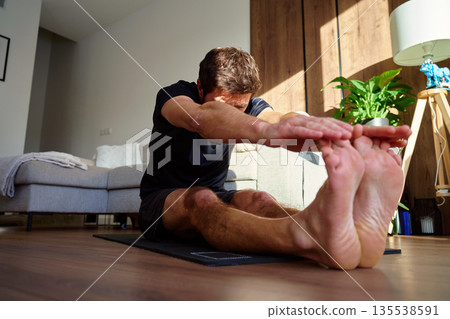 Man stretching during home workout in living room Man stretching during home workout in living room 135538591