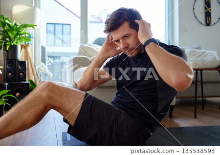 Man doing abdominal crunch exercise on fitness mat at home 135538593