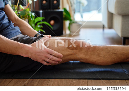 Man holding leg muscle after workout during home exercise Man holding leg muscle after workout during home exercise 135538594