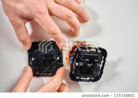 Electrician installing electrical light switch in wall Electrician installing electrical light switch in wall 135538601