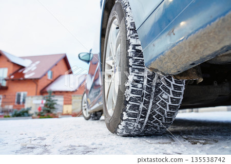Car with winter tires parked on snowy road near house Car with winter tires parked on snowy road near house 135538742