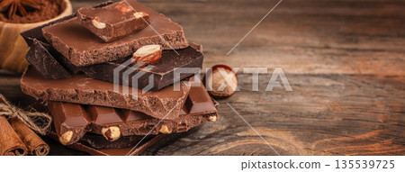 Stack of milk and dark chocolate bars with nuts on wooden background. copy space 135539725