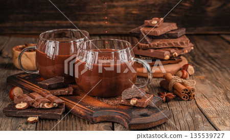Two cups of hot chocolate with chocolate bars and spices on rustic wooden table 135539727