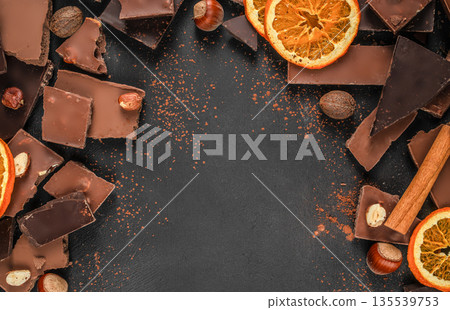 Dark chocolate background with cocoa powder, nuts and orange slices, copy space 135539753