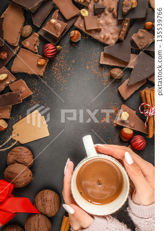 Hands holding cup of hot chocolate with chocolate pieces on dark background with copy space Hands holding cup of hot chocolate with chocolate pieces on dark background with copy space 135539766