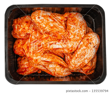 Marinated raw chicken wings in black plastic tray isolated on white background Marinated raw chicken wings in black plastic tray isolated on white background 135539794